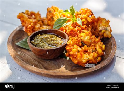 Perkedel jagung or bakwan jagung, corn fritters with sambal hijau (green chili sauce) served on ...