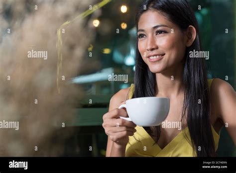 Happy young beautiful Asian woman drinking coffee and thinking at the coffee shop Stock Photo ...