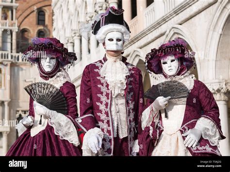 Three masked people wearing red and white carnival costumes, Carnevale di Venezia, Venice, Italy ...