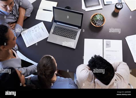 Giving it their best shot. Shot of an office table with staff using a ...