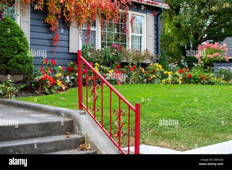 A bright red metal handrail leading up four concrete steps to a walkway Stock Photo - Alamy