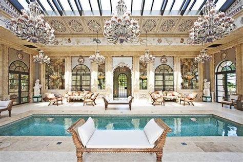 an indoor swimming pool with chandeliers hanging from the ceiling and chairs around it