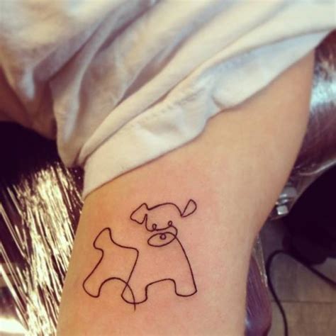 Continuous line drawing style dog tattoo on the bicep.