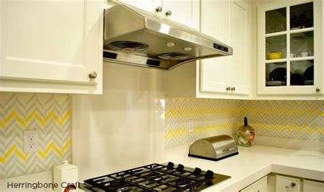 a kitchen with white cabinets and yellow chevron backsplashes on the wall