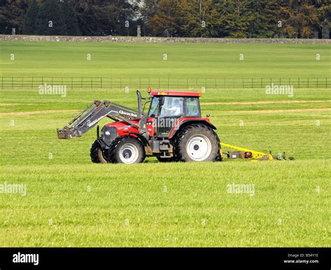 Red Farm tractor towing a large mowing machine Stock Photo - Alamy