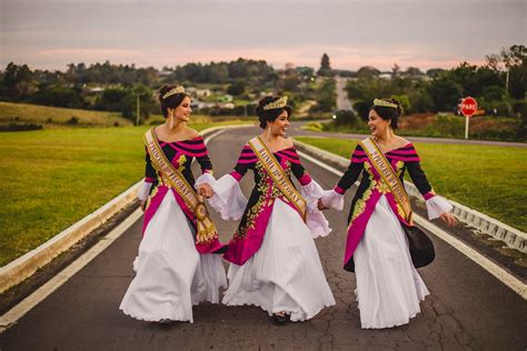Glad ethnic girlfriends in trendy dresses holding hands on road · Free Stock Photo