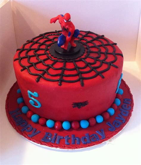 a spiderman birthday cake with red frosting and blue candies on the bottom