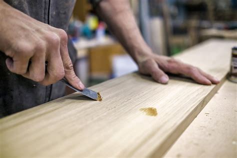 close up of man using wood filler or wood putty to fill holes in wood ...