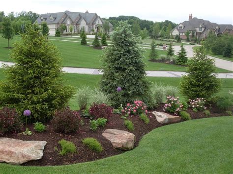 Sweet! This berm features evergreen screening, boulder accents, and pops of color achieved with ...