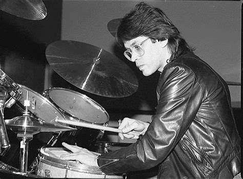 black and white photograph of a woman playing the drums in front of a drum set