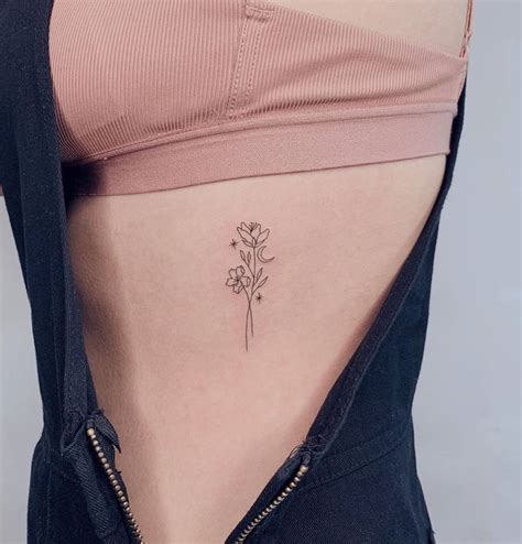 Fine line flower tattoo on rib