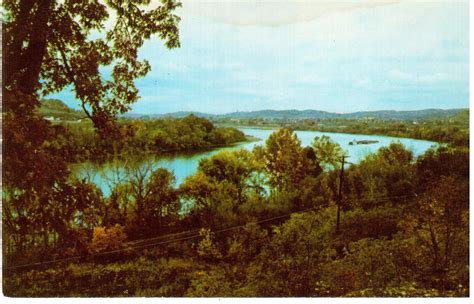 a painting of a river surrounded by trees and hills in the distance with blue water