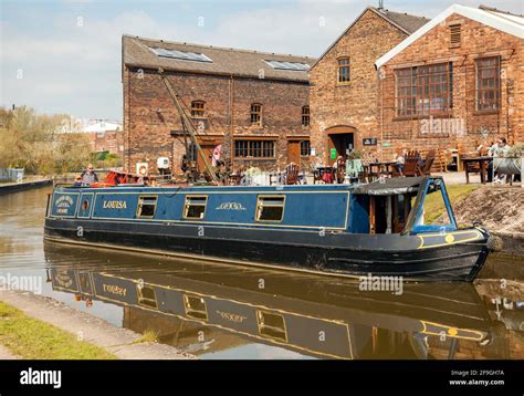 Canal narrowboat passing the Middleport pottery factory on the Trent and Mersey canal as it ...