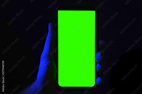 Mobile phone in young man hand. Use smartphone with green screen on red ...