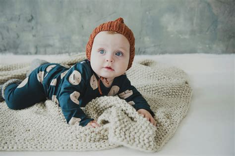 Baby In Blue Onesie Lying On White Textile · Free Stock Photo