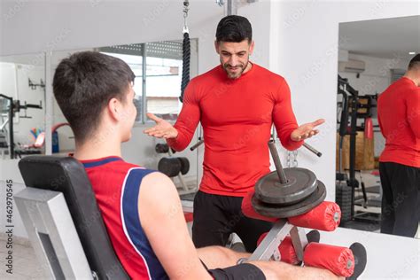 gym teacher teaching a student to do their exercises and train in a gym ...