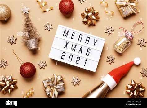 Lightbox with text MERRY XMAS 2021 and golden christmas decor on beige background. Creative ...