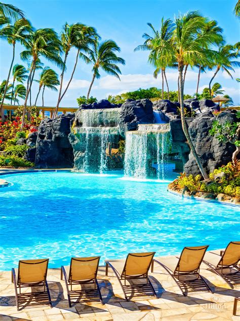 Swim under the waterfall to reach the water slide and whirlpool at Kona Pool at Hilton Waikoloa ...