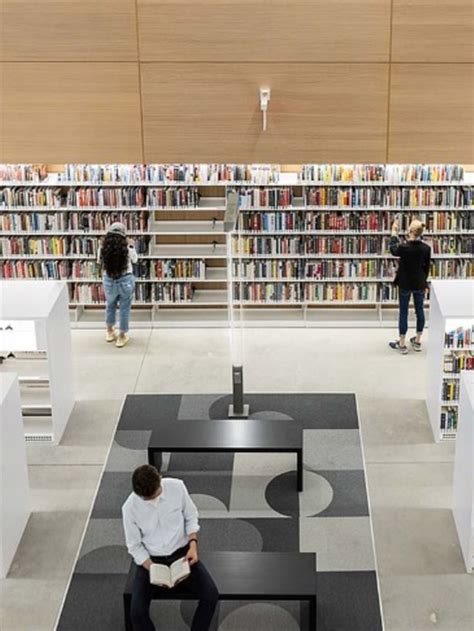 two people are sitting on benches in the middle of a library with ...