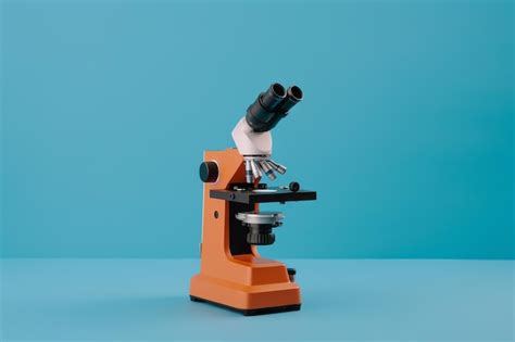 Premium Photo | A red microscope with a hand holding a black lens.