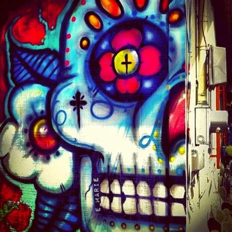 a colorful painting on the side of a building that has a skull and cross painted on it