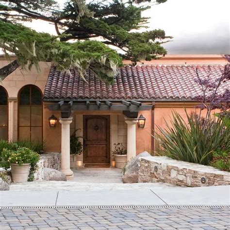 the front entrance to a house with potted plants and trees in front of it