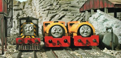 three thomas the tank engine cars are sitting on train tracks in front of a mountain