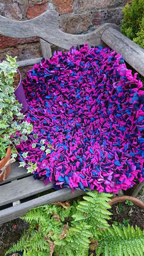 purple and blue rug sitting on top of a wooden bench next to green planters