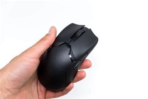 Hand holds the Viper Ultimate wireless gaming mouse by Razer in black, close-up on a white ...