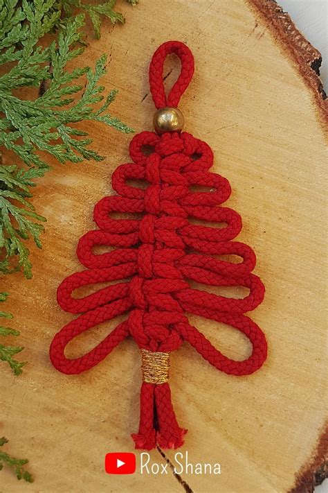 a crocheted christmas tree ornament on a piece of wood with pine needles