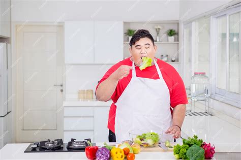 Premium Photo | Overweight man eating salad in the kitchen