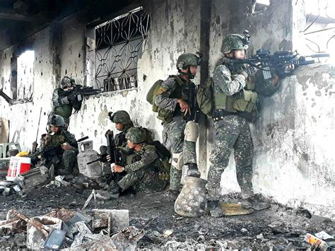 Philippine Army infantrymen watch the windows while others take a rest inside a bombed out bldg ...