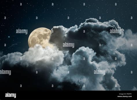 Full moon behind the clouds on a starry night Stock Photo - Alamy