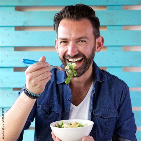 Portrait of cheerful man eating salad Stock Photo | Adobe Stock