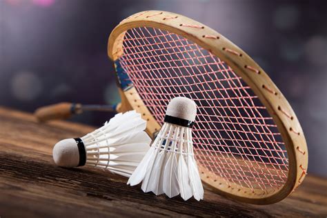 two badminton racquets are sitting next to each other on a wooden table