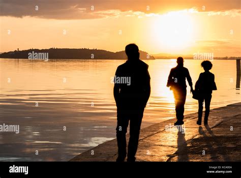 Silhouette of people walking on a sidewalk at sunset Stock Photo - Alamy