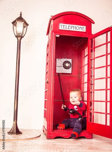 small american child sits in a red telephone booth, baby Stock Photo | Adobe Stock