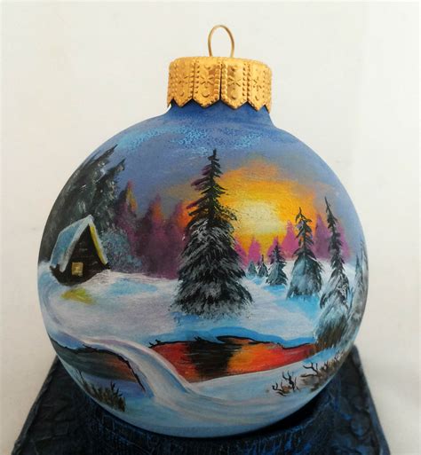 a painted ornament with a cabin in the background