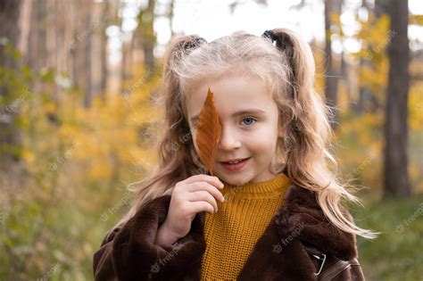 Premium Photo | Happy little child girl smiling, covering her face with autumn leave in the fall ...