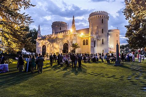 people standing in front of a castle at night with the sun setting on it's roof