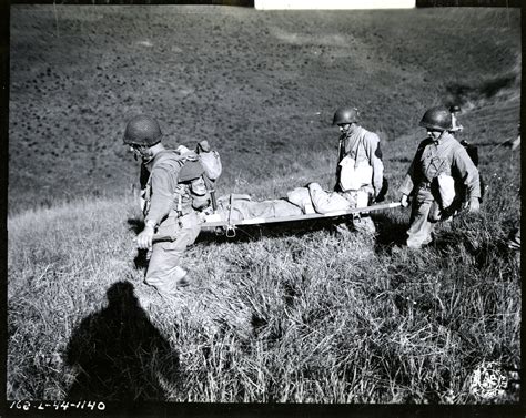 Wounded soldier being carried from battle zone during maneuvers near Camp San Luis Obispo ...