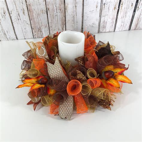 a candle is sitting on top of a wreath with leaves and pumpkins around it