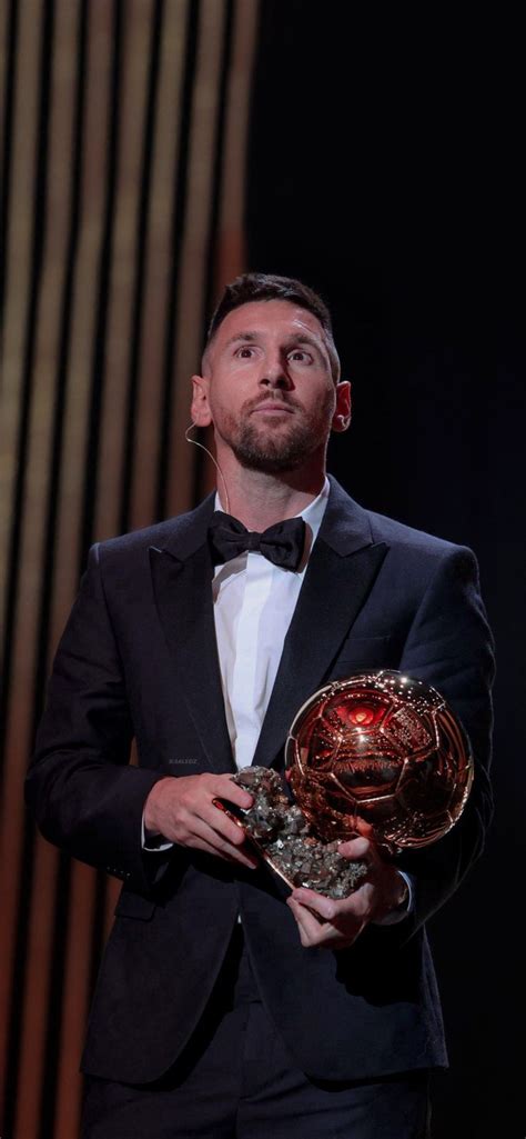 a man in a tuxedo holding a ballon d'or award on stage