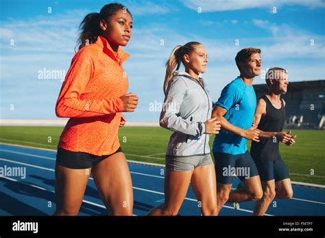 Group of diverse sports person practicing running in stadium. Male and female athletes running ...