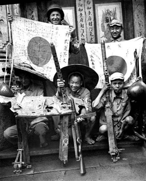 US soldier, Chinese soldier, and Chinese guerrilla fighters displaying captured Japanese flags ...