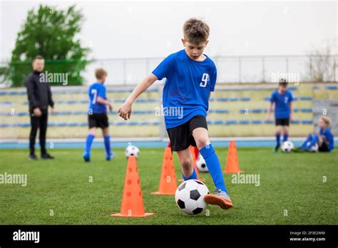 Boys attending soccer training on school field. Young man coaching children on physical ...