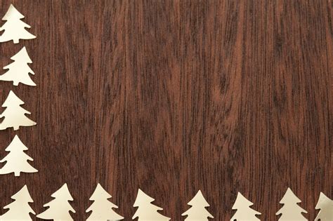 Photo of golden cut out trees lying border on wood | Free christmas images