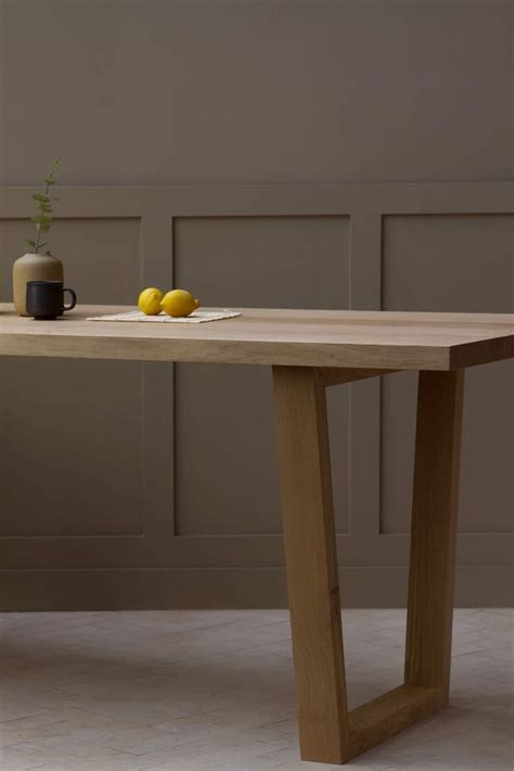 a wooden table with two lemons on it and a vase next to it,