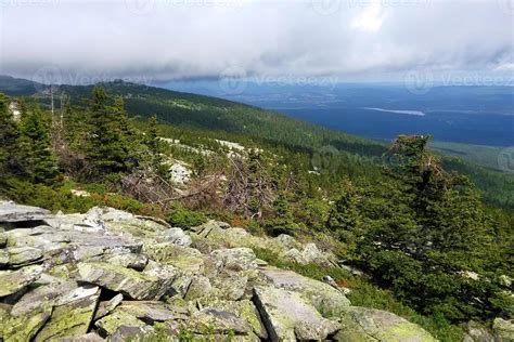 Travel to Ural mountains, Russia. The view from a peak on the mountains, forest and cloudy sky ...