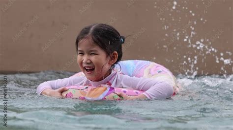 Smiling cute little girl playing water and kicking feet water in ...